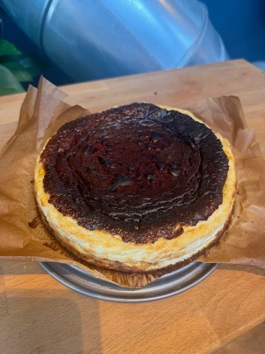 Ganzer Käsekuchen mit dunkel gebackener Oberfläche auf Backpapier