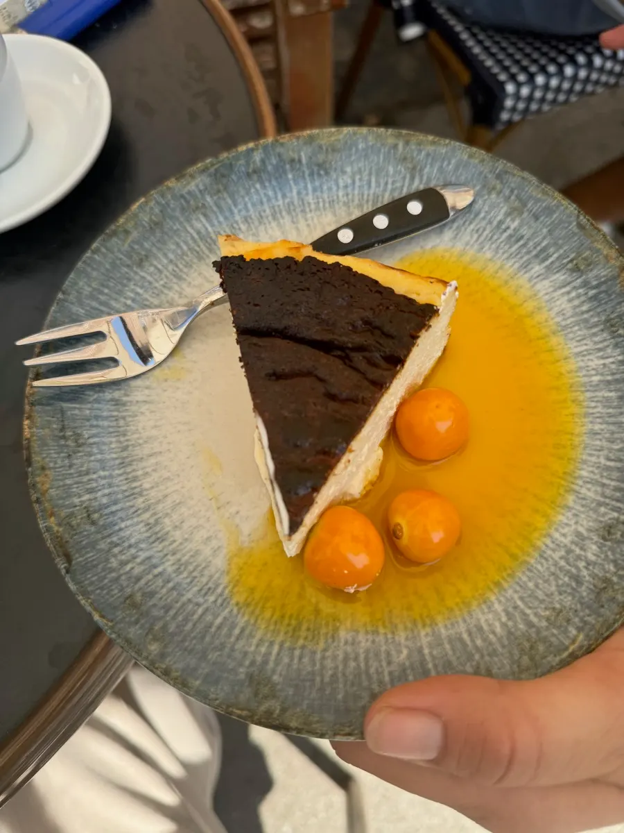 Stück Käsekuchen mit Physalis und Fruchtsauce auf blauem Teller